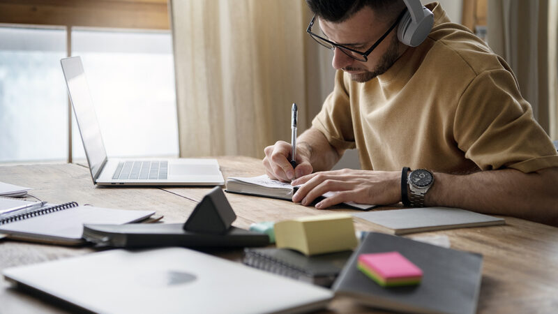 young man writing notebook study session